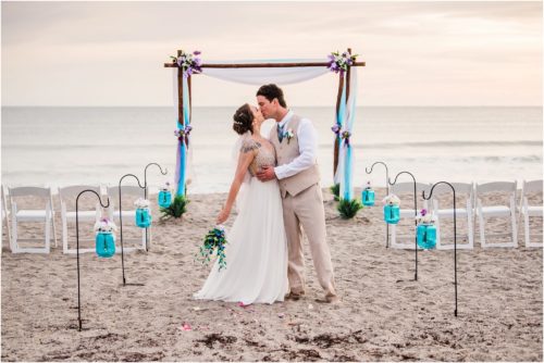 Bride and groom kissing in front of arch during Cocoa Beach Sunrise Wedding
