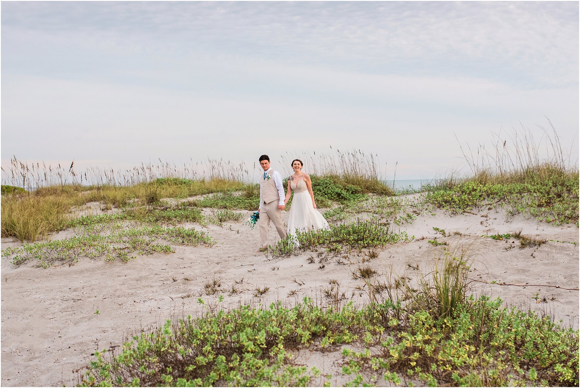 bride and groom walking on dunes during Cocoa Beach Sunrise Wedding