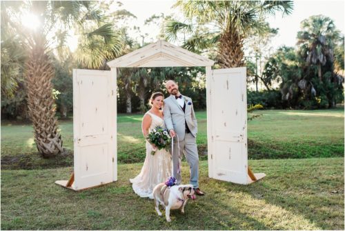Couple with their dog under white door frame arches at Banyan Estate Wedding