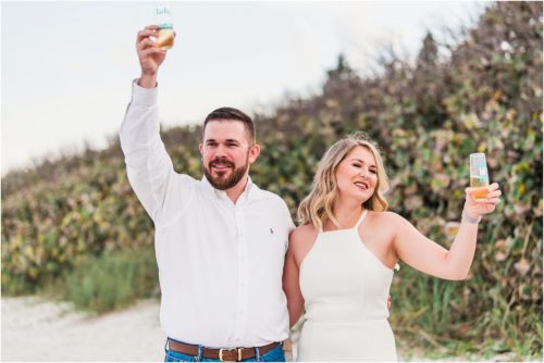Newly engaged couple toasting everyone on beach during Satellite beach proposal