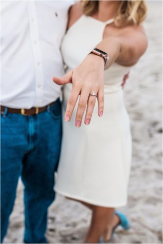 Girl in white dress showing off engagement ring during Surprise Proposal