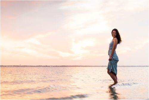 Girl standing in Indian River Lagoon with sun setting in the background