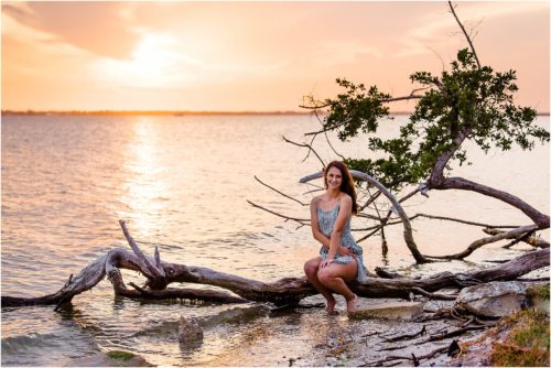 Girl sitting on driftwood by Indian river Lagoon Melbourne Beach Senior Photography