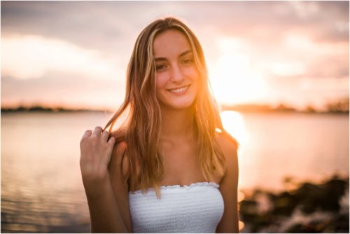 Girl twirling hair with sun setting Riverside Park Senior Portraits