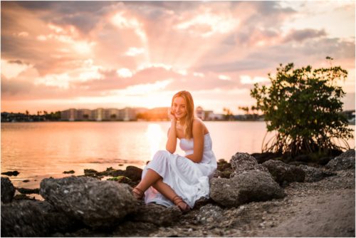 Girl sitting on rocks with sun setting
