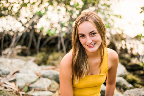 girl in yellow top sitting on rocks