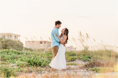 Couple hugging by dunes Cocoa beach engagement