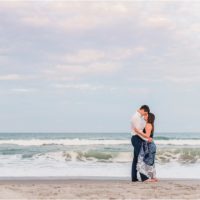 Couple hugging with ocean in background Best Engagement Session Beach Locations