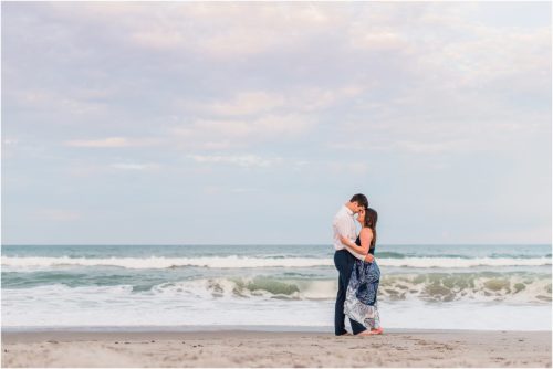 Couple hugging with ocean in background Best Engagement Session Beach Locations