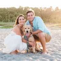 Couple cuddling with dog on beach Cocoa Beach Engagement