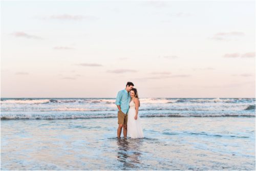 Couple standing in waves on beach