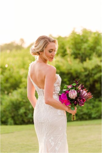 Bride looking at pink bouquet during Melbourne Beach vow renewal inspired shoot