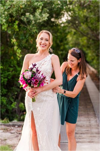 Fifth Ave Bridal owner Julia fixing back of dress during Melbourne Beach vow renewal inspired shoot