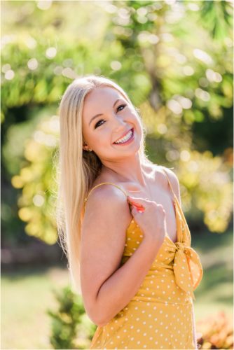 Girl with blond hair and yellow romper smiling in the sun