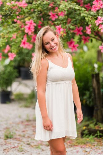 Senior in front of pink hibiscus tree laughing Senior Photography at Rockledge Gardens