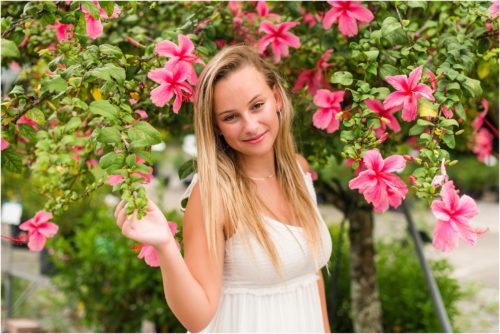 Senior in front of pink hibiscus tree laughing Senior Photography at Rockledge Gardens