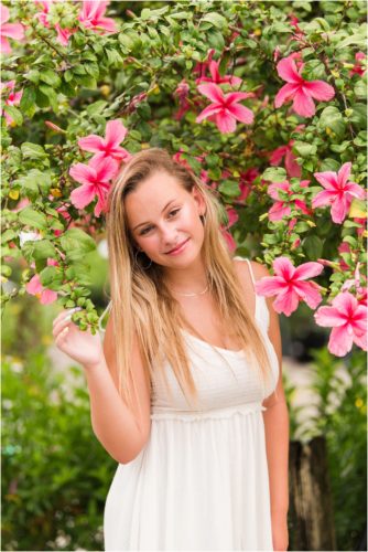 Senior in front of pink hibiscus tree laughing Senior Photography at Rockledge Gardens