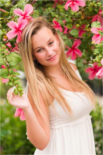Senior in front of pink hibiscus tree laughing Senior Photography at Rockledge Gardens