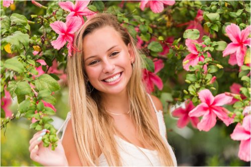 Senior in front of pink hibiscus tree laughing Senior Photography at Rockledge Gardens