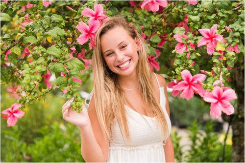 Senior in front of pink hibiscus tree laughing Senior Photography at Rockledge Gardens