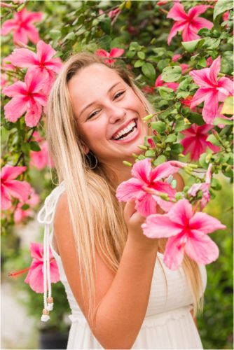 Senior in front of pink hibiscus tree laughing Senior Photography at Rockledge Gardens