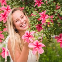 Senior in front of pink hibiscus tree laughing Senior Photography at Rockledge Gardens