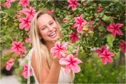 Senior in front of pink hibiscus tree laughing Senior Photography at Rockledge Gardens