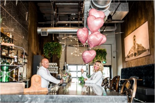 Bride and groom sitting at bar in 28 North Gastropub. Groom serving bride a cocktail