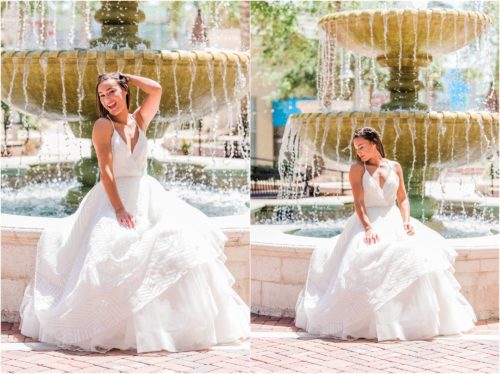 Bride sitting on edge of fountain lifting her Haley Paige wedding dress up.