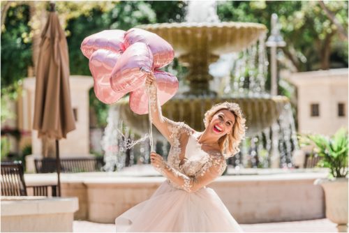 Bride holding balloons with fountain in the background