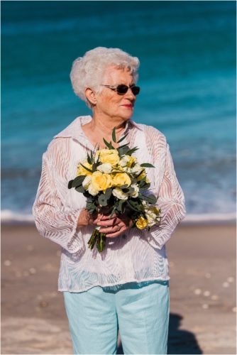 Grandmother holding the bride's yellow flowers on beach Grandparents in your wedding photography