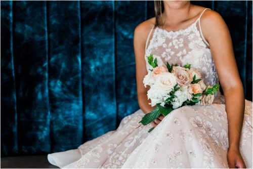 Bride on blue couch with flowers from Fern and Curl