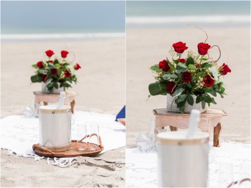 beach blanket setup with red roses and blue pillows during surprise proposal on Cocoa Beach