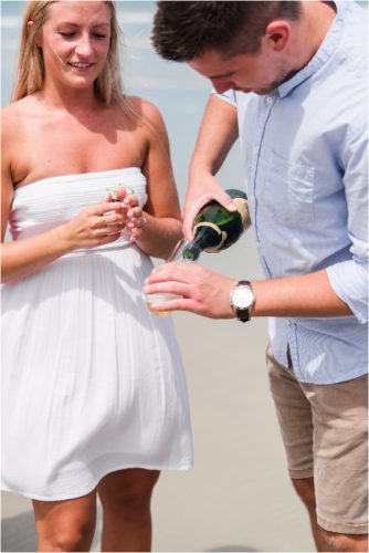 Pouring champagne after proposing on the beach