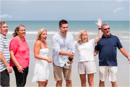 Popping champagne on the beach after Surprise Proposal