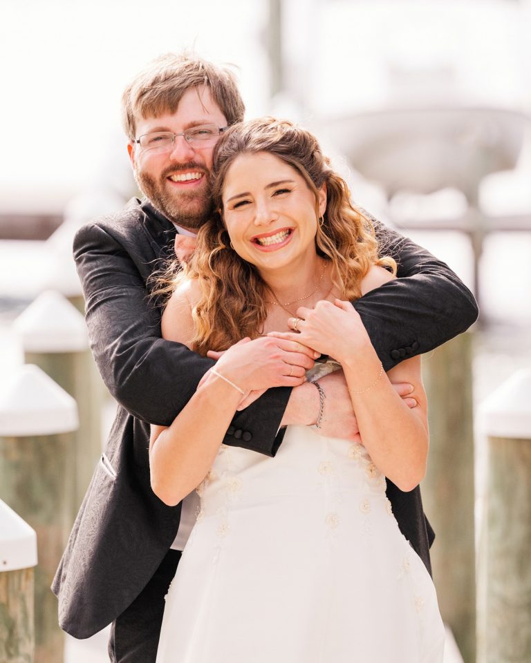 Newlyweds laughing together during wedding portraits in Melbourne Beach, Florida
