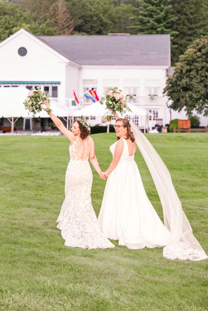 two brides holding up bouquets after ceremony at the Quaker hill County Club in Pawling New York