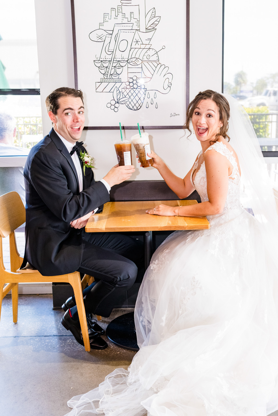 Couple sitting at Starbucks in their wedding clothes sharing a coffee
