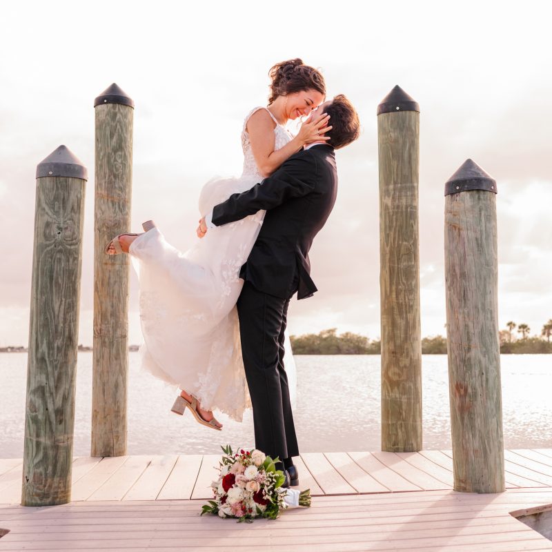 Man lifting bride in air at the end of the dock at the Eau Gallie Yacht Club