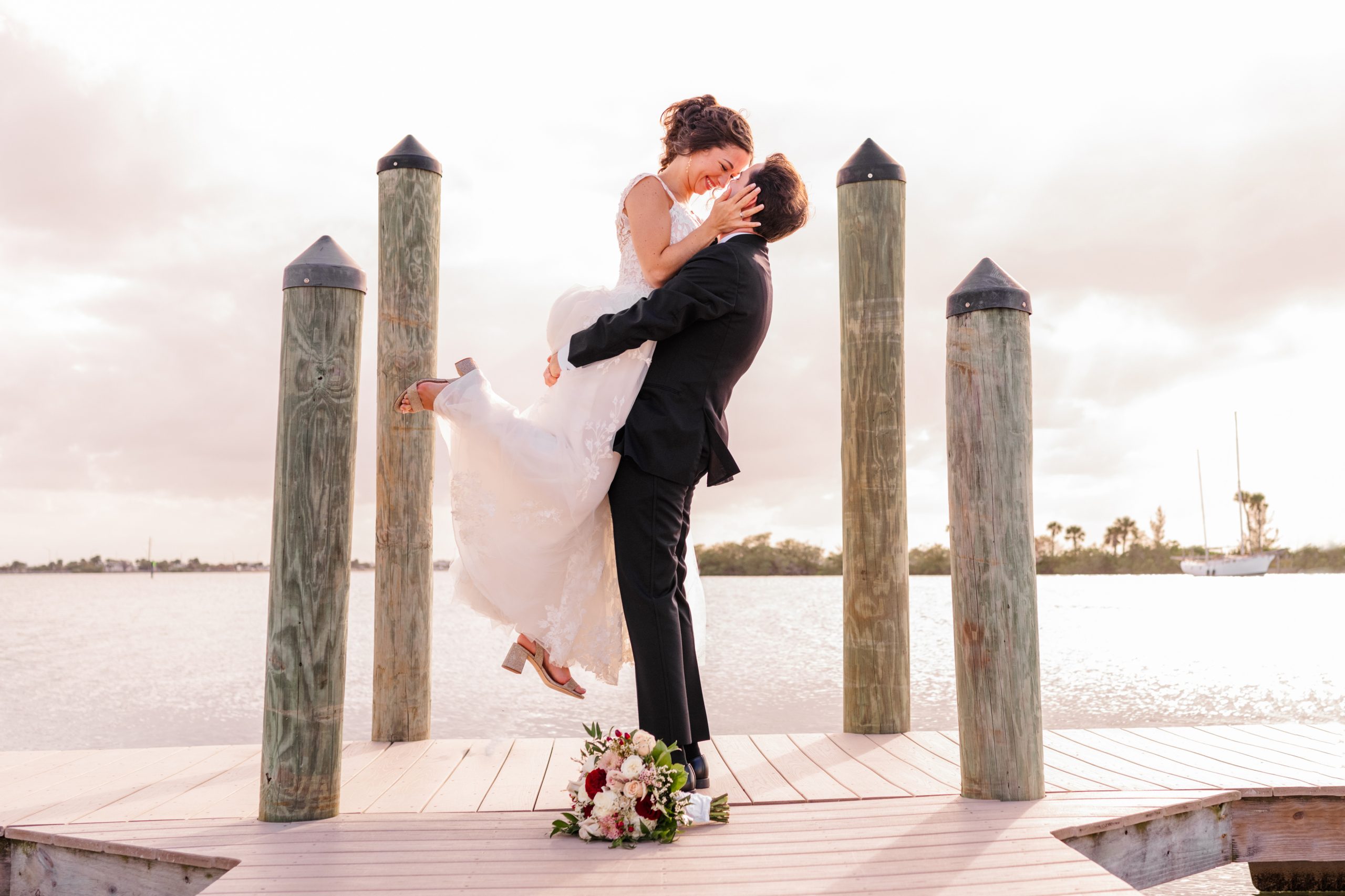 Man lifting bride in air at the end of the dock at the Eau Gallie Yacht Club