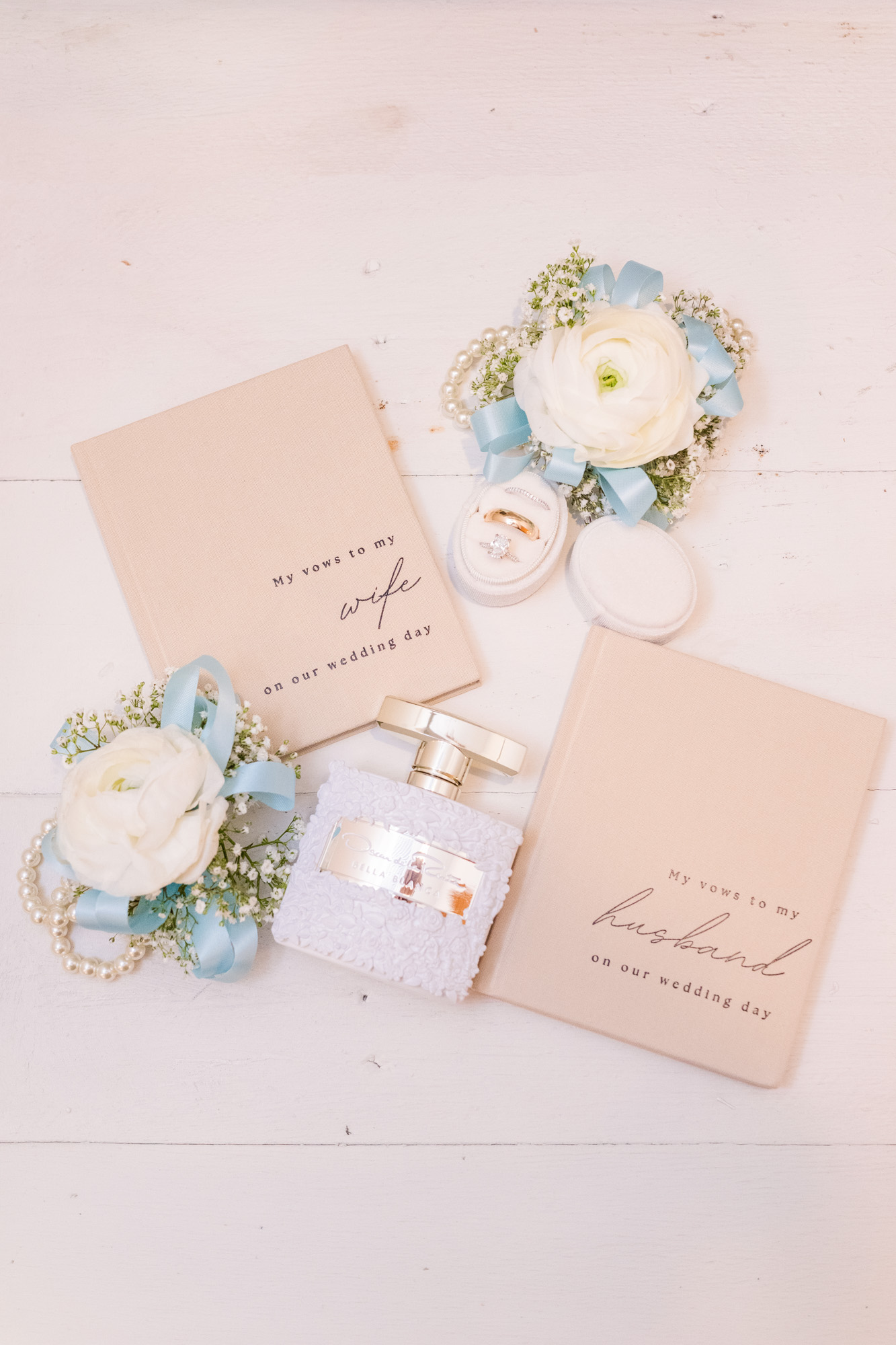 Wedding vow books, rings, perfume and white flowers with pale blue ribbon at Harbour House Oceanfront.