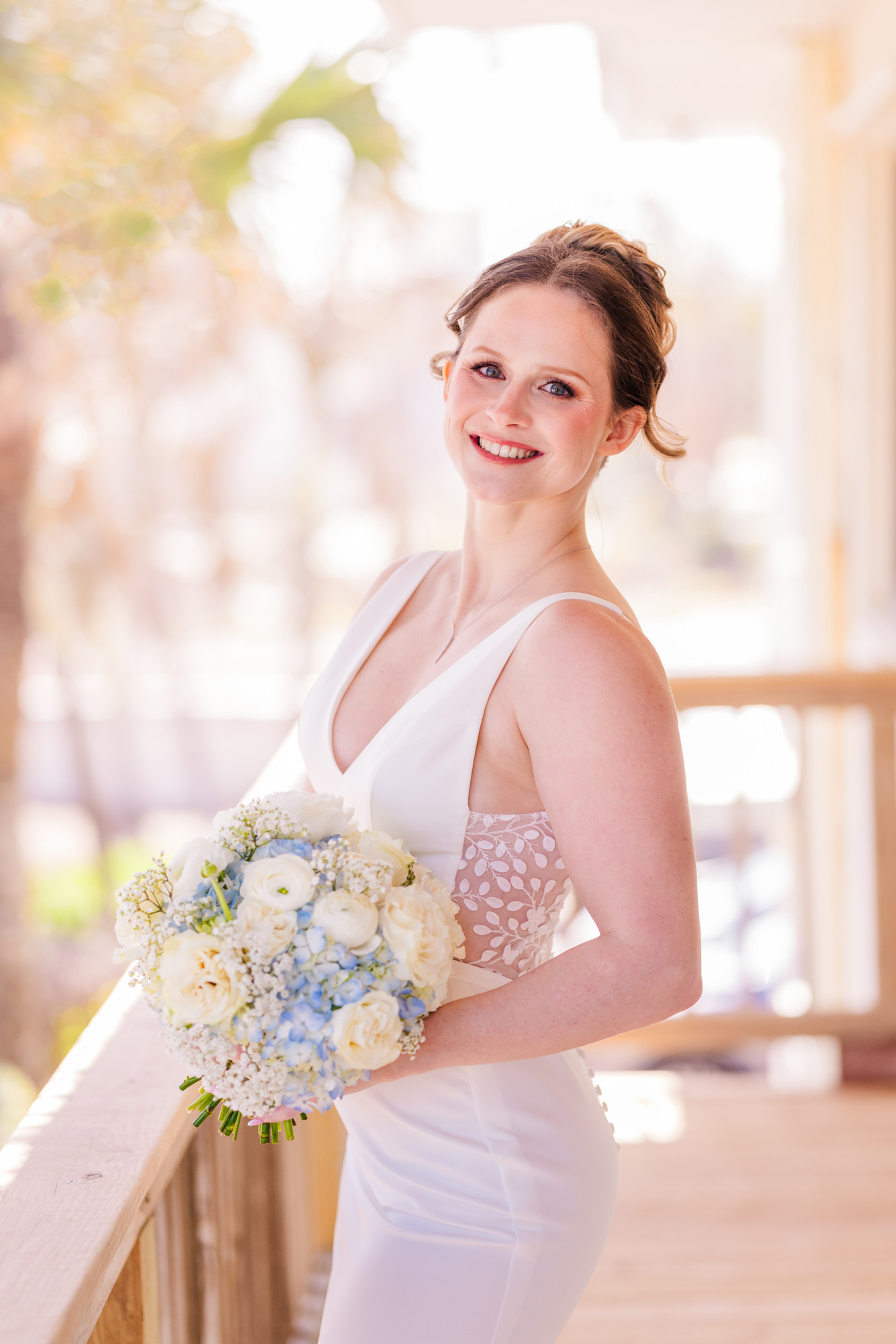 Bride holding a white and pale blue bouquet on the balcony at Harbour House Oceanfront.