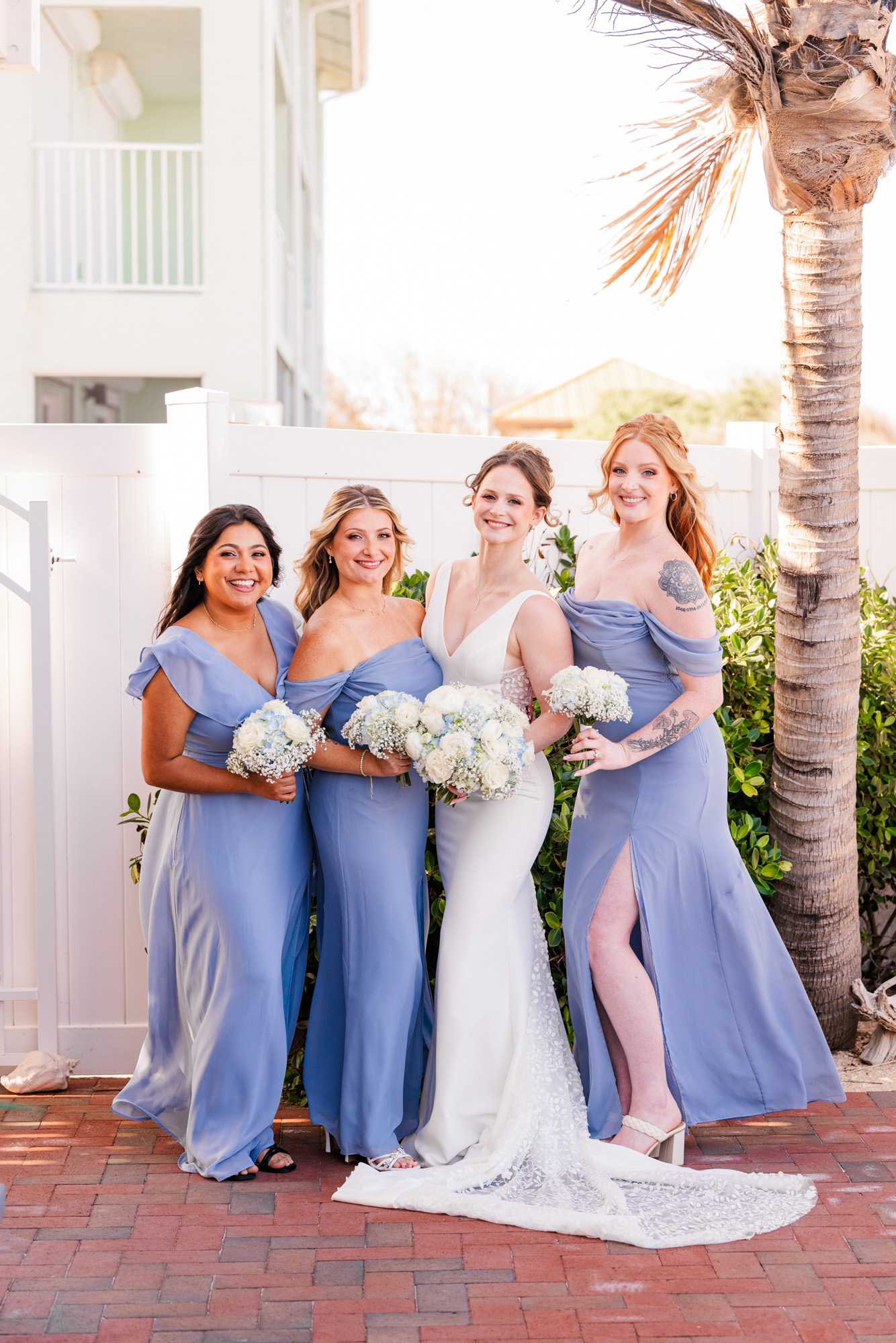 Bride posing with her bridesmaids in dusty blue dresses at Harbour House Oceanfront.