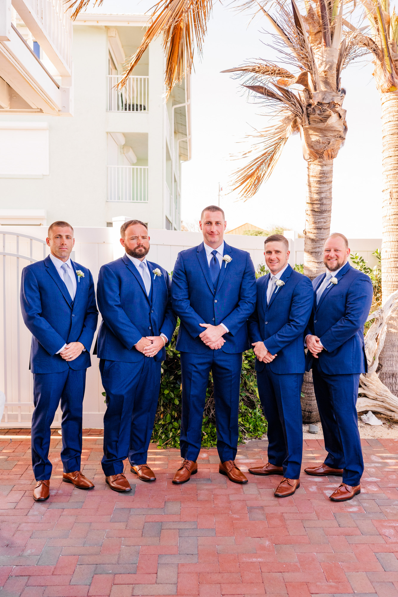 Groomsmen in matching navy blue suits posing outside Harbour House Oceanfront.