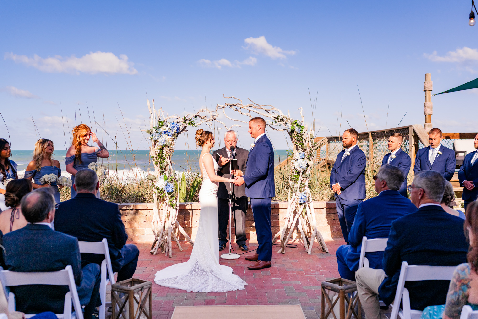 Outdoor oceanfront wedding ceremony at Harbour House with a driftwood floral arch.
