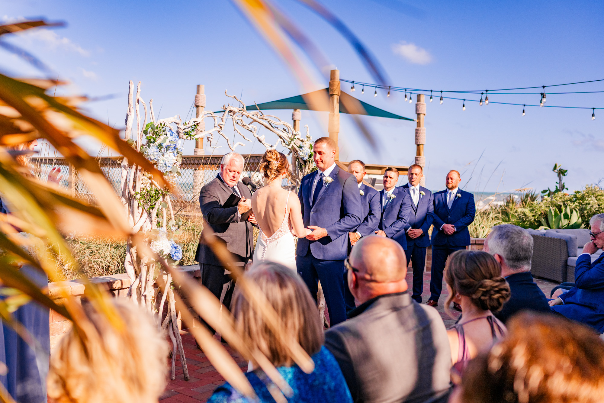 Oceanfront wedding ceremony at Harbour House with the wedding party standing beside the couple.