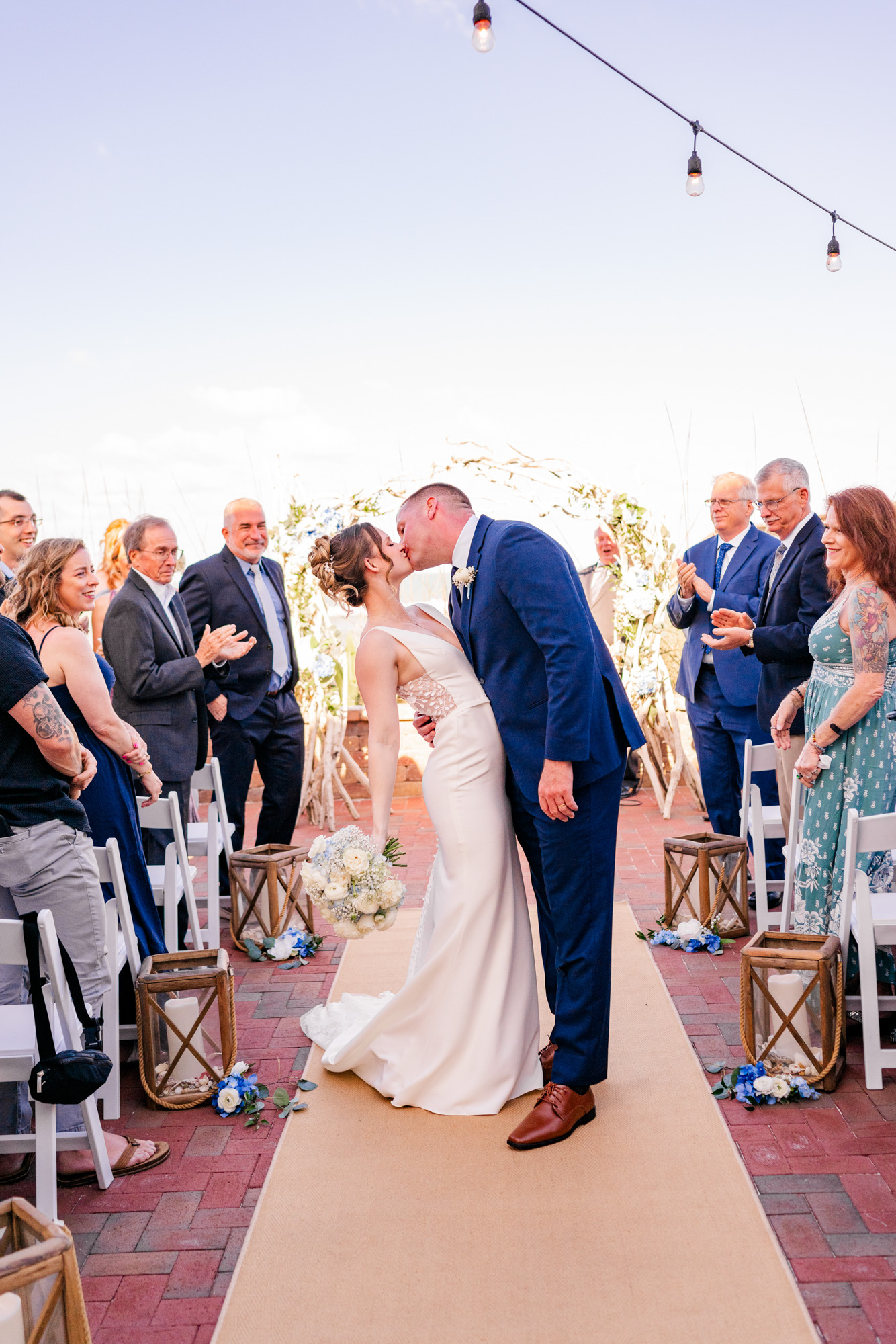 Bride and groom sharing their first kiss as wedding guests applaud at Harbour House Oceanfront.