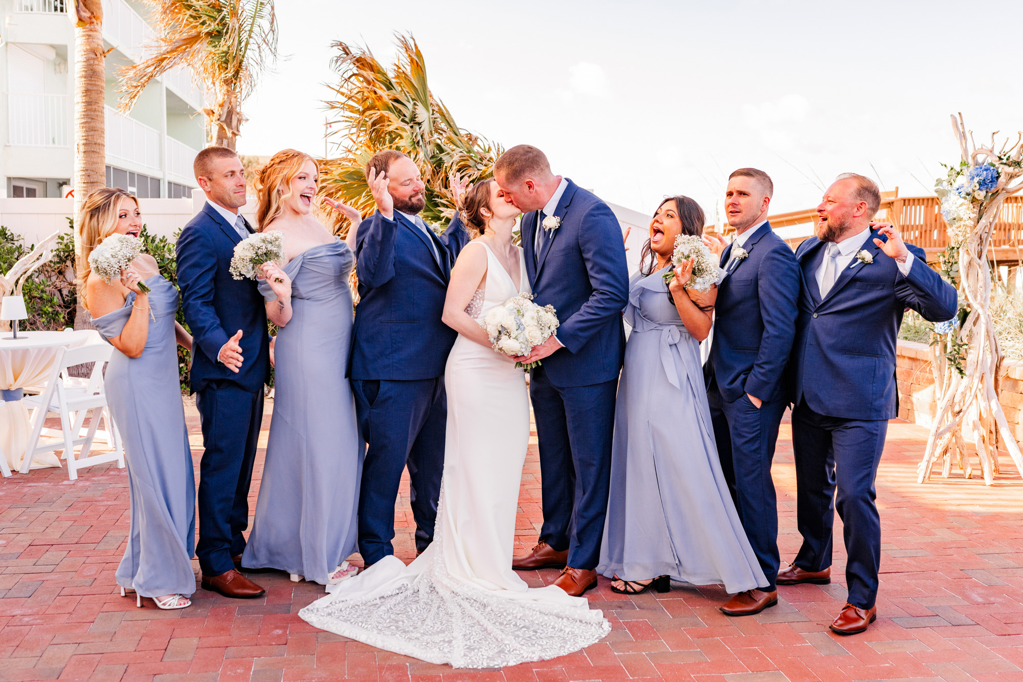 Bride and groom kissing while their wedding party celebrates around them at Harbour House Oceanfront.