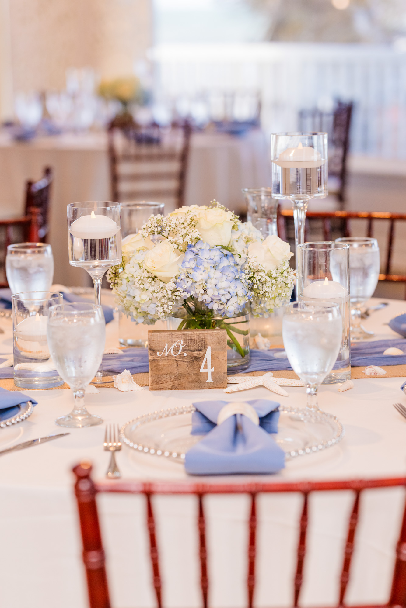 Blue and white wedding reception centerpiece with hydrangeas, roses and floating candles.