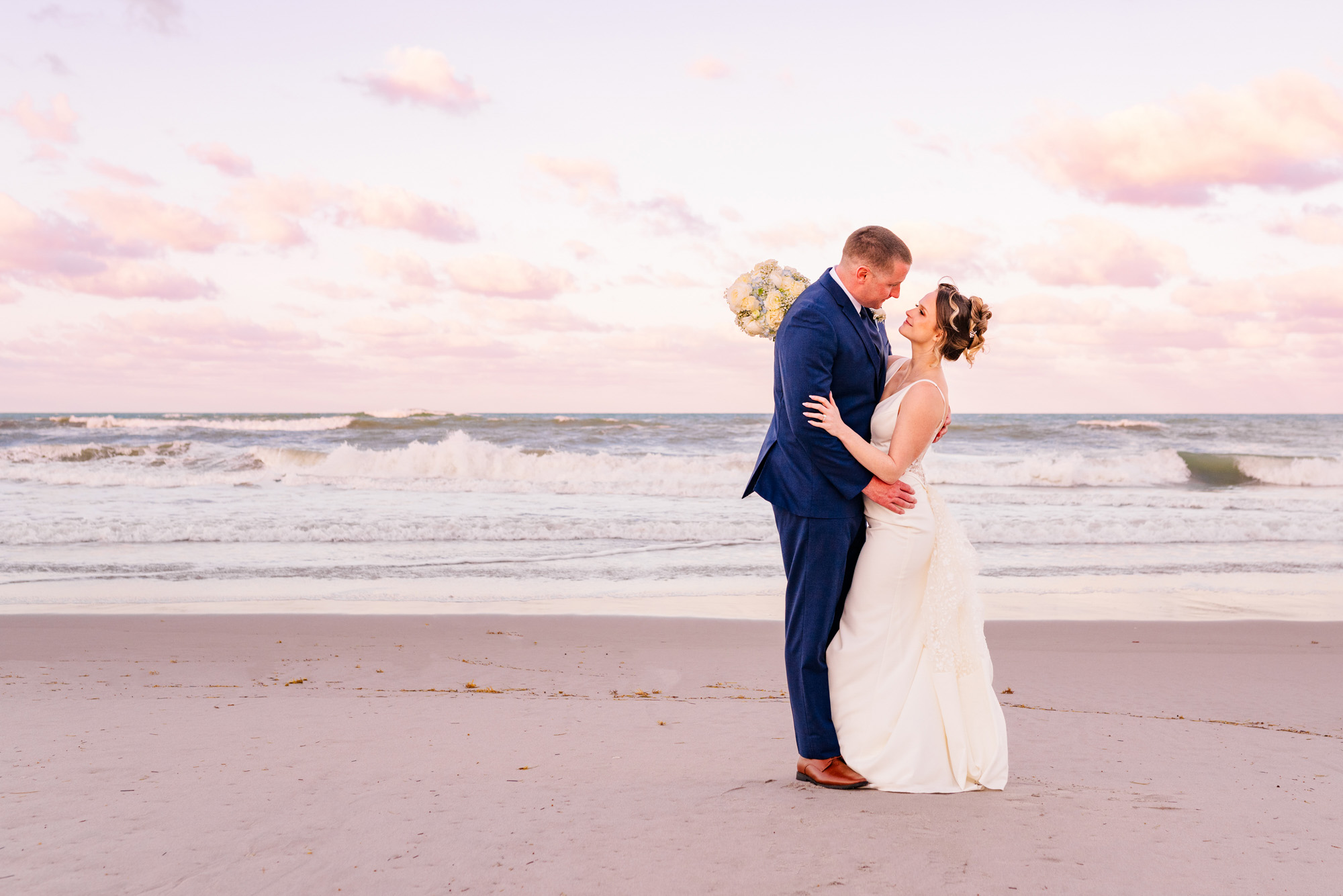 Bride and groom embracing on the beach at sunset after their Harbour House Oceanfront wedding.